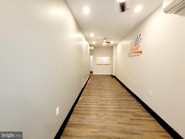 hall featuring a wall mounted AC, recessed lighting, light wood-style flooring, and baseboards