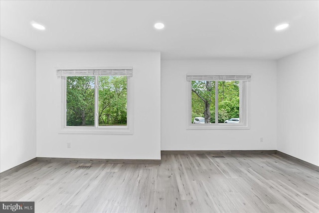 spare room featuring plenty of natural light, wood finished floors, recessed lighting, and baseboards