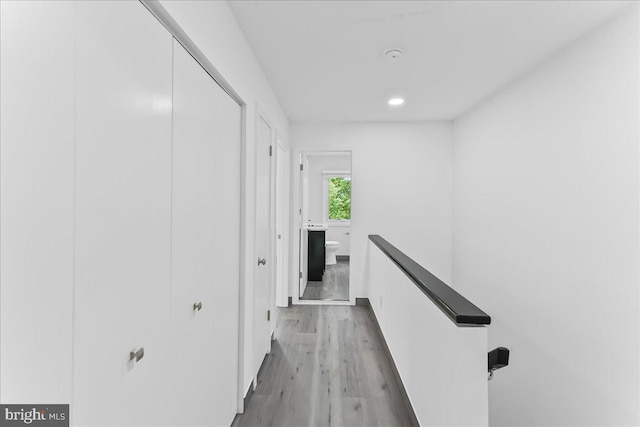 hallway featuring an upstairs landing, wood finished floors, recessed lighting, and baseboards