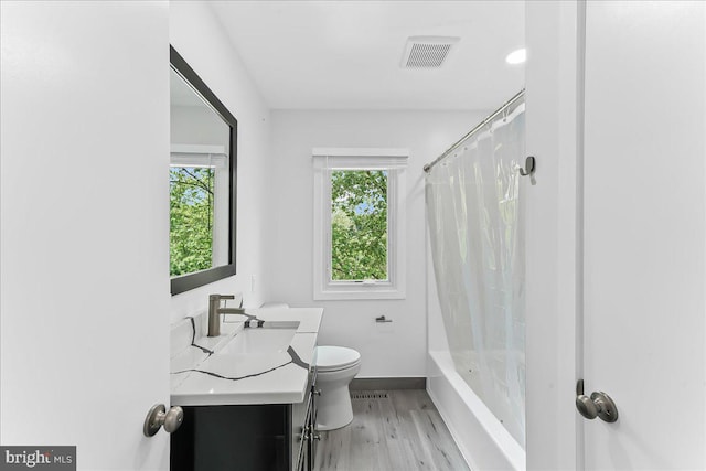bathroom featuring toilet, wood finished floors, vanity, baseboards, and shower / bath combo with shower curtain