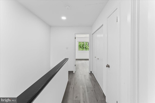 hallway with light wood-type flooring, an upstairs landing, and recessed lighting