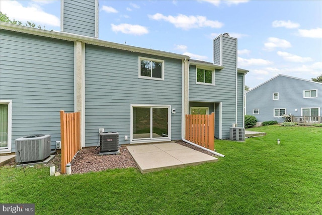 rear view of property featuring a chimney, central AC, a lawn, and a patio