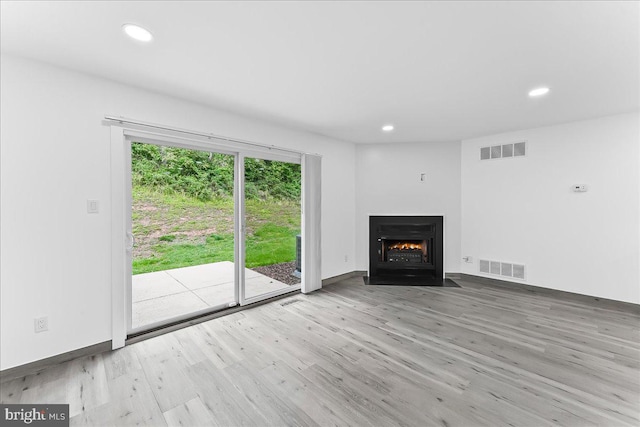 unfurnished living room with wood finished floors, recessed lighting, a fireplace with flush hearth, and baseboards