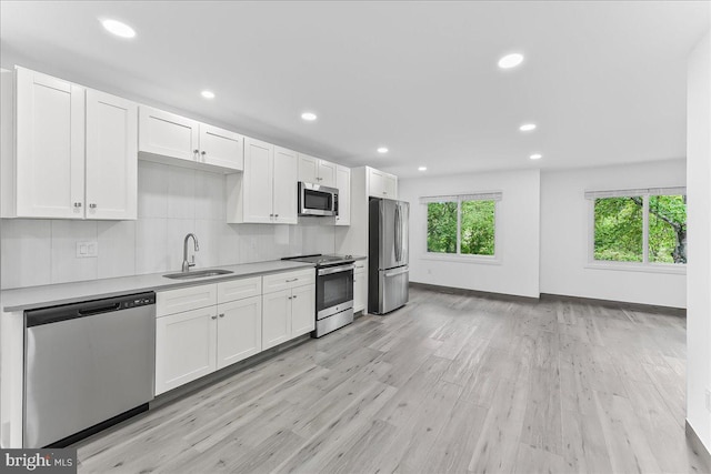 kitchen featuring stainless steel appliances, a sink, healthy amount of natural light, white cabinets, and recessed lighting