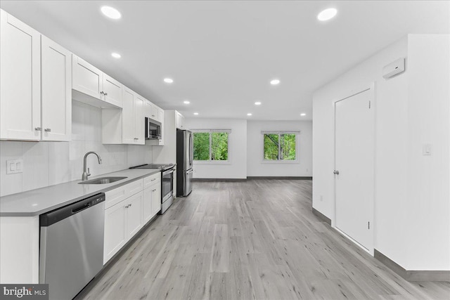kitchen featuring stainless steel appliances, a sink, recessed lighting, white cabinets, and light wood-type flooring