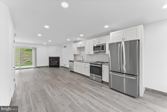 kitchen with appliances with stainless steel finishes, a sink, white cabinets, and recessed lighting