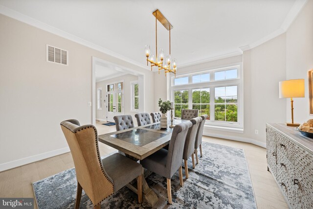dining area featuring a chandelier, baseboards, crown molding, and light wood finished floors