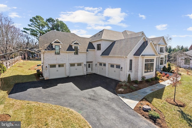 view of front of property with driveway, a front lawn, an attached garage, and roof with shingles