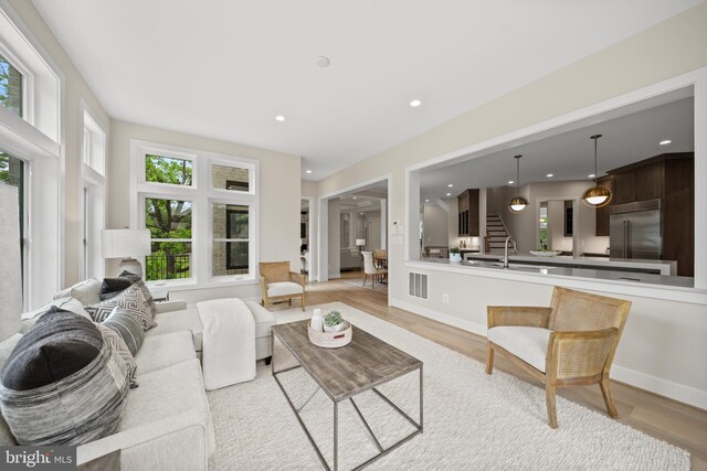 living room featuring light wood-style flooring, healthy amount of natural light, recessed lighting, stairs, and baseboards