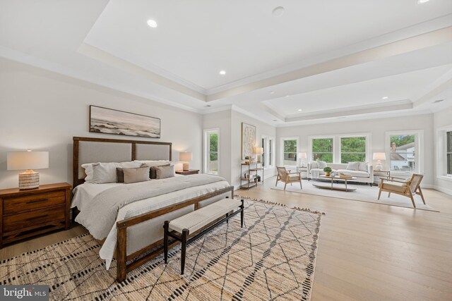 bedroom with a tray ceiling, wood finished floors, recessed lighting, and ornamental molding