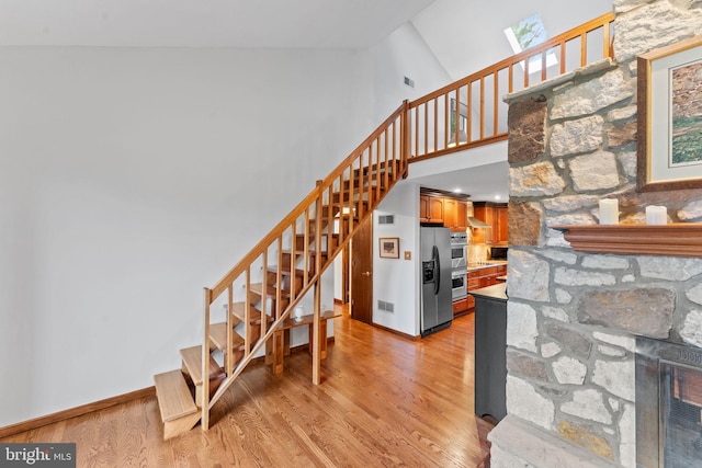 4 Fox Ridge Rd, Glenmoore, PA 19343 - stairs featuring wood finished floors, a stone fireplace, a skylight, a towering ceiling, and baseboards