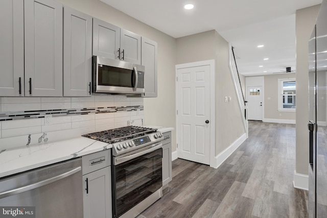 6706 Marsden St, Philadelphia, PA 19135 - kitchen featuring stainless steel appliances, backsplash, light stone countertops, dark wood-style floors, and gray cabinetry