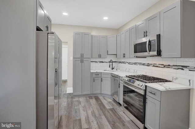 6706 Marsden St, Philadelphia, PA 19135 - kitchen featuring appliances with stainless steel finishes, a sink, gray cabinetry, light wood-type flooring, and recessed lighting