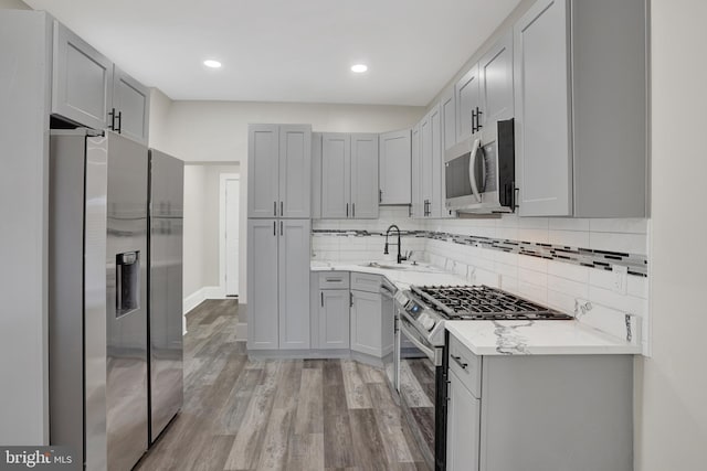 6706 Marsden St, Philadelphia, PA 19135 - kitchen featuring appliances with stainless steel finishes, light wood-type flooring, gray cabinetry, tasteful backsplash, and a sink