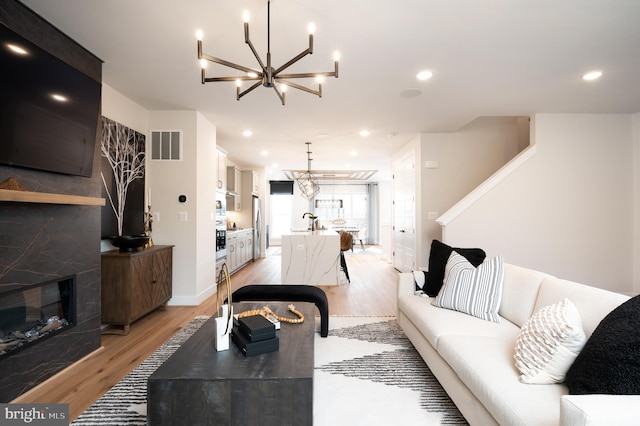 42152 Stone Press Ter, Brambleton, VA 20148 - living room featuring a chandelier, light wood finished floors, a glass covered fireplace, recessed lighting, and baseboards