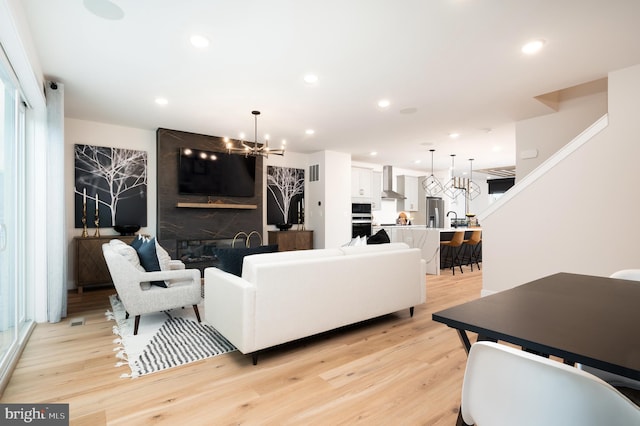 42152 Stone Press Ter, Brambleton, VA 20148 - living room featuring a chandelier, light wood-style floors, recessed lighting, and a large fireplace
