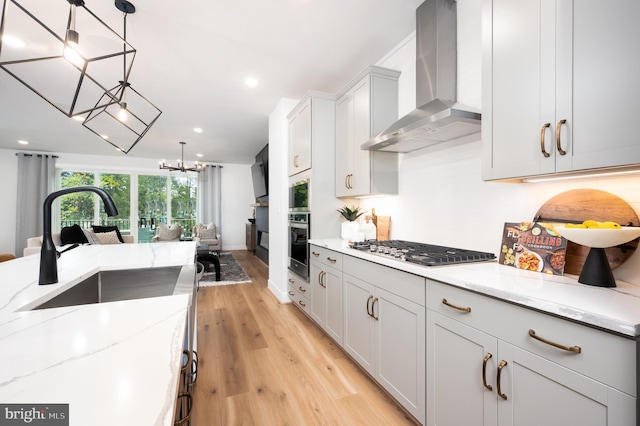 42152 Stone Press Ter, Brambleton, VA 20148 - kitchen with wall chimney exhaust hood, stainless steel appliances, open floor plan, a chandelier, and light wood-style flooring