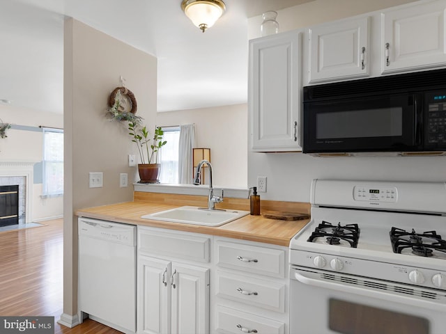 411 Stonebridge Blvd, New Castle, DE 19720 - kitchen featuring white appliances, a sink, white cabinetry, light wood-type flooring, and a premium fireplace