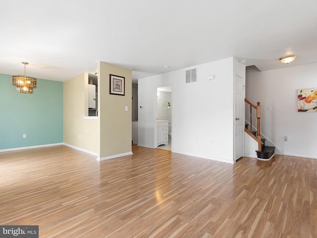 411 Stonebridge Blvd, New Castle, DE 19720 - unfurnished living room with a chandelier, stairs, baseboards, and light wood finished floors