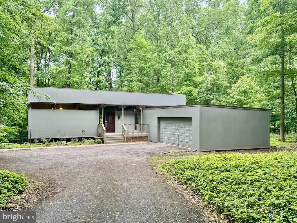 2502 Caves Forest Rd, Owings Mills, MD 21117 - view of front of property featuring asphalt driveway, an attached garage, a porch, and a wooded view
