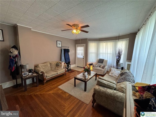 living area featuring ceiling fan, crown molding, and baseboards