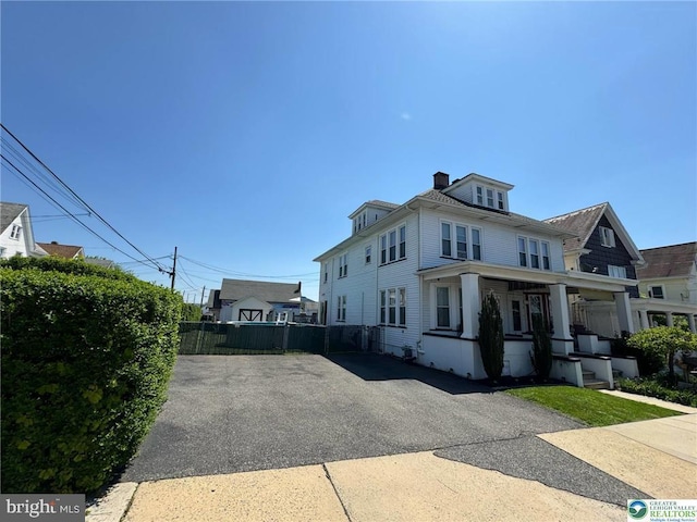 view of property exterior featuring fence, a porch, and a chimney