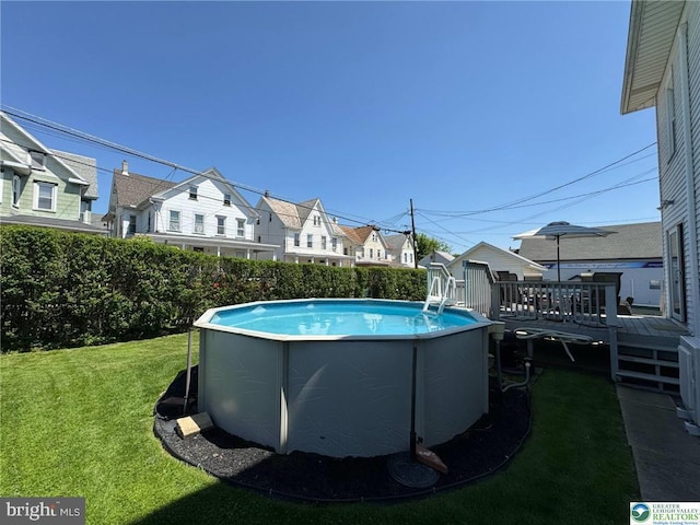 view of swimming pool featuring a yard, a wooden deck, and a residential view