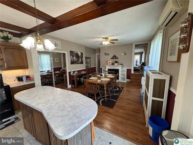 kitchen with a wall unit AC, light countertops, black range with electric cooktop, a ceiling fan, and a kitchen island