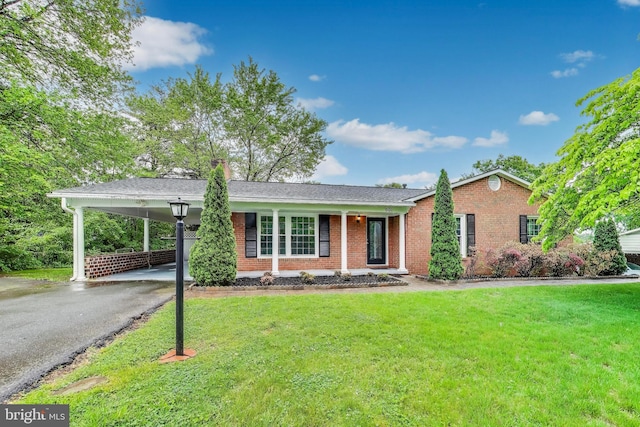 single story home featuring driveway, brick siding, a front yard, and a carport