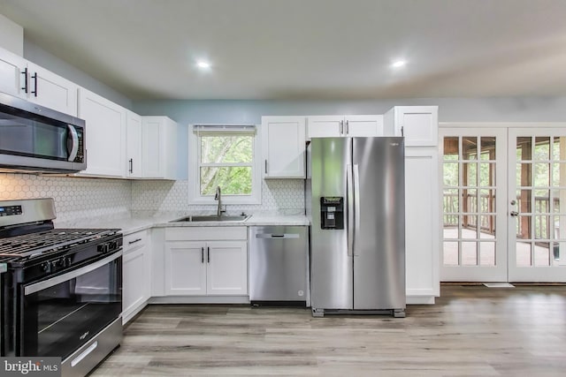 kitchen featuring stainless steel appliances, a sink, light countertops, white cabinets, and decorative backsplash
