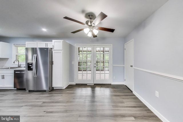 kitchen with stainless steel appliances, white cabinetry, ceiling fan, and light wood-type flooring
