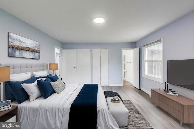 bedroom featuring multiple closets, light wood-style floors, baseboards, and connected bathroom