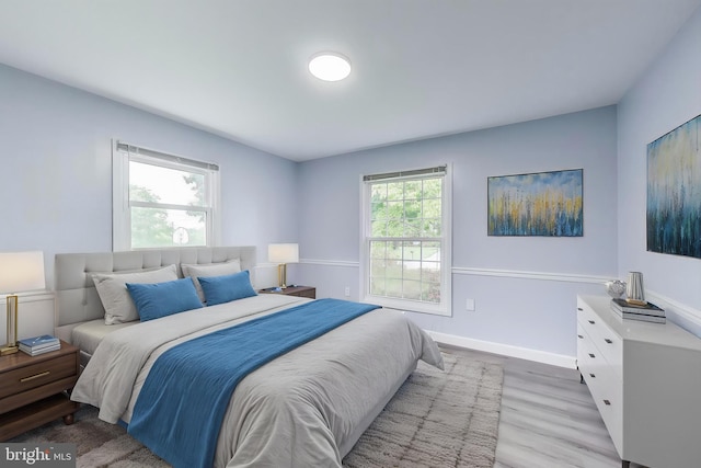 bedroom featuring light wood finished floors and baseboards