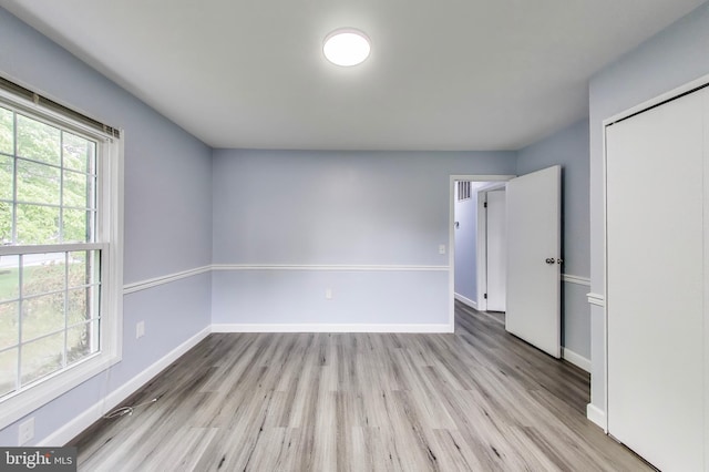 unfurnished bedroom with light wood-type flooring, baseboards, and a closet