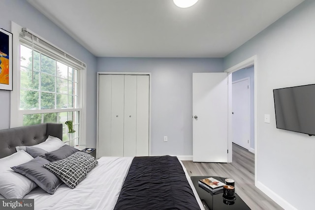 bedroom with light wood-style floors, baseboards, and a closet
