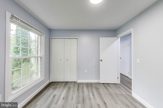 unfurnished bedroom featuring baseboards, light wood-type flooring, and a closet