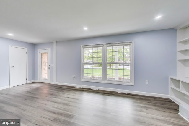 unfurnished living room with wood finished floors, baseboards, and recessed lighting