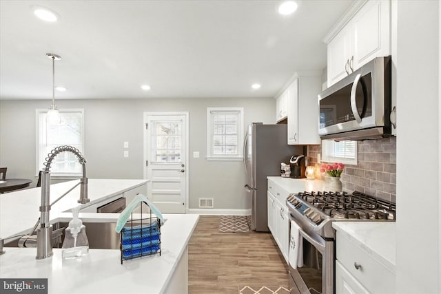 8907 Mavis Ave, Baltimore, MD 21236 - kitchen with appliances with stainless steel finishes, white cabinetry, light countertops, light wood-style flooring, and tasteful backsplash