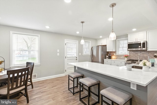 8907 Mavis Ave, Baltimore, MD 21236 - kitchen featuring appliances with stainless steel finishes, decorative backsplash, a breakfast bar area, white cabinets, and recessed lighting