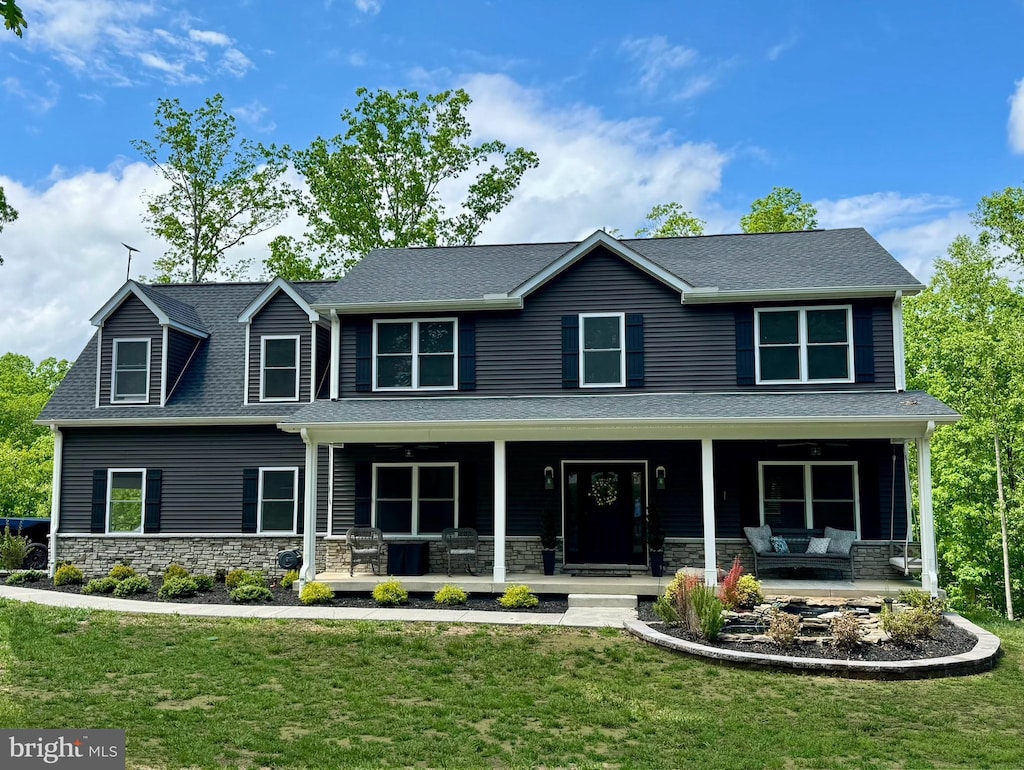 view of front of property with stone siding, a front yard, and a porch