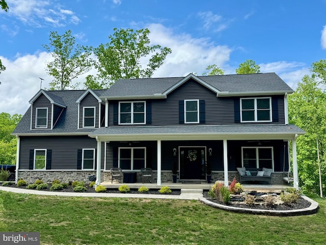 view of front of property with stone siding, a front yard, and a porch