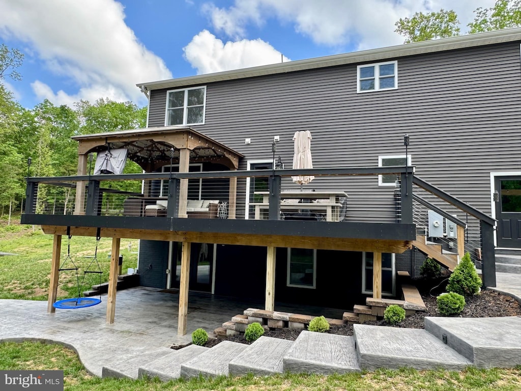 rear view of property featuring a wooden deck, stairs, and a patio