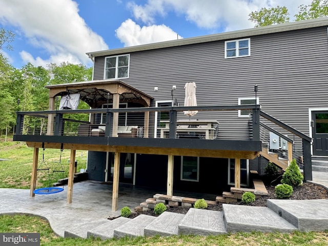 rear view of property featuring a wooden deck, stairs, and a patio