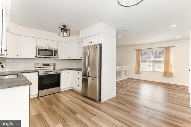 8838 Mckinley Ct, Hummelstown, PA 17036 - kitchen featuring stainless steel appliances, a sink, dark countertops, light wood finished floors, and tasteful backsplash