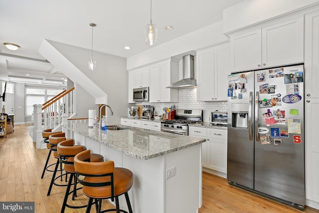 419 S E Ave, Baltimore, MD 21224 - kitchen featuring appliances with stainless steel finishes, wall chimney range hood, a sink, a kitchen island with sink, and white cabinets