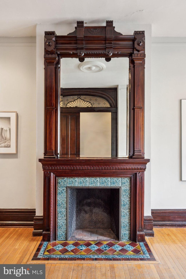 detailed view of baseboards, wood finished floors, and a premium fireplace
