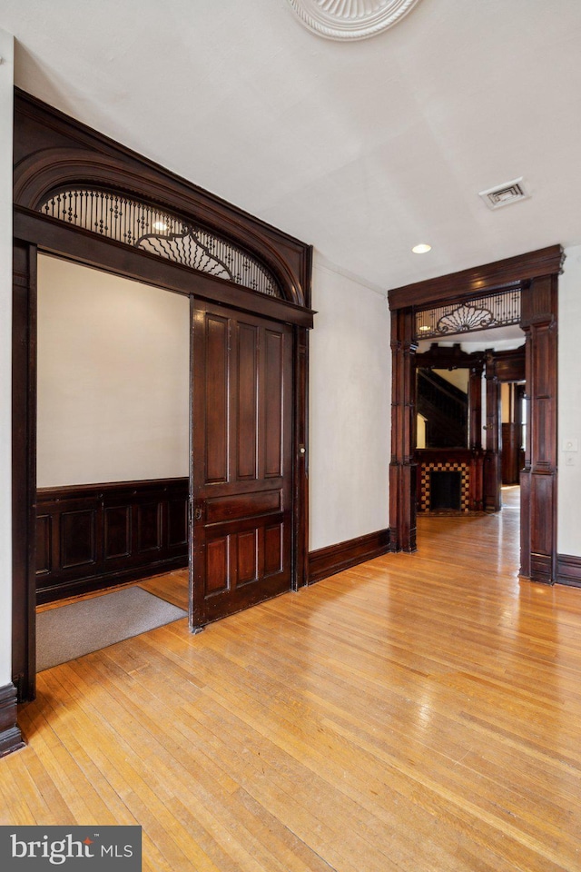 hallway with light wood-style floors, recessed lighting, a wainscoted wall, and baseboards