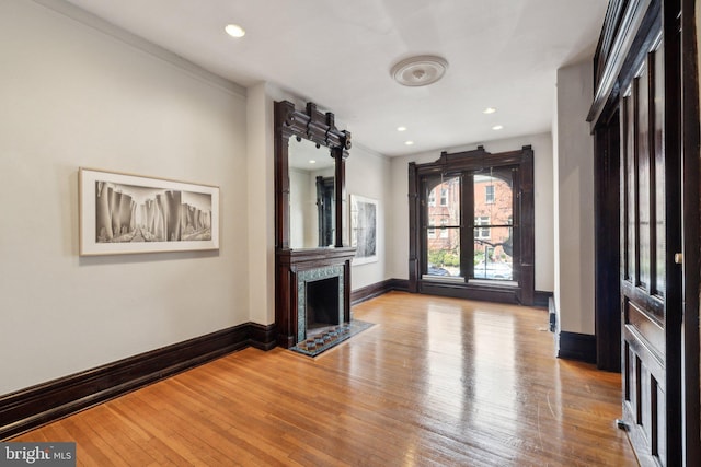 unfurnished living room with wood finished floors, a fireplace, baseboards, and recessed lighting