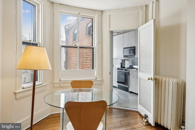 dining space with radiator heating unit and wood finished floors