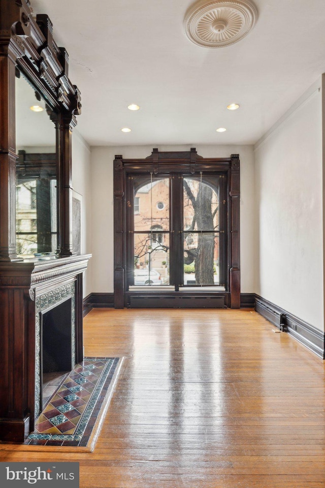 unfurnished living room with a fireplace, baseboards, wood-type flooring, and recessed lighting